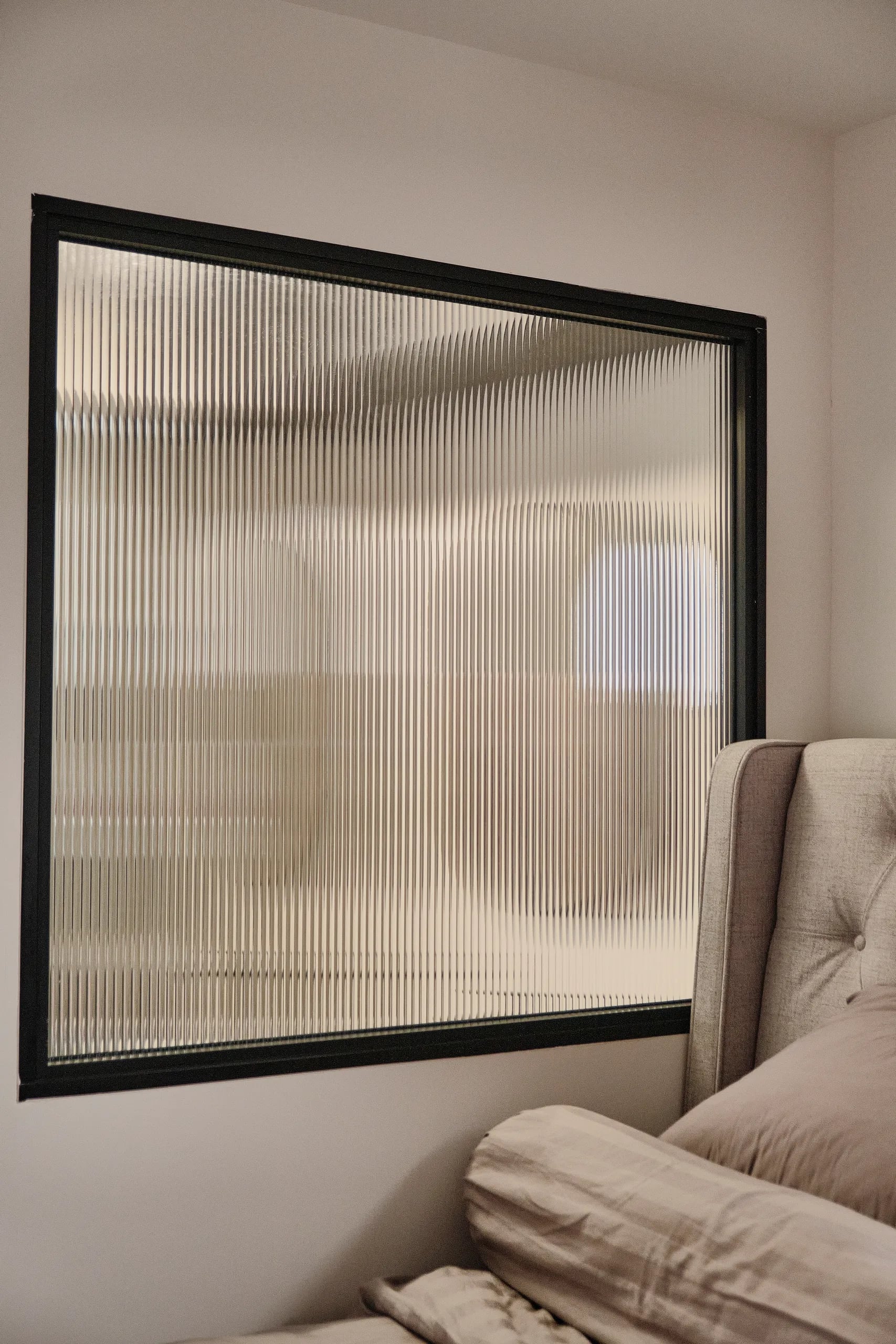 A large window with black frame and reeded glass
