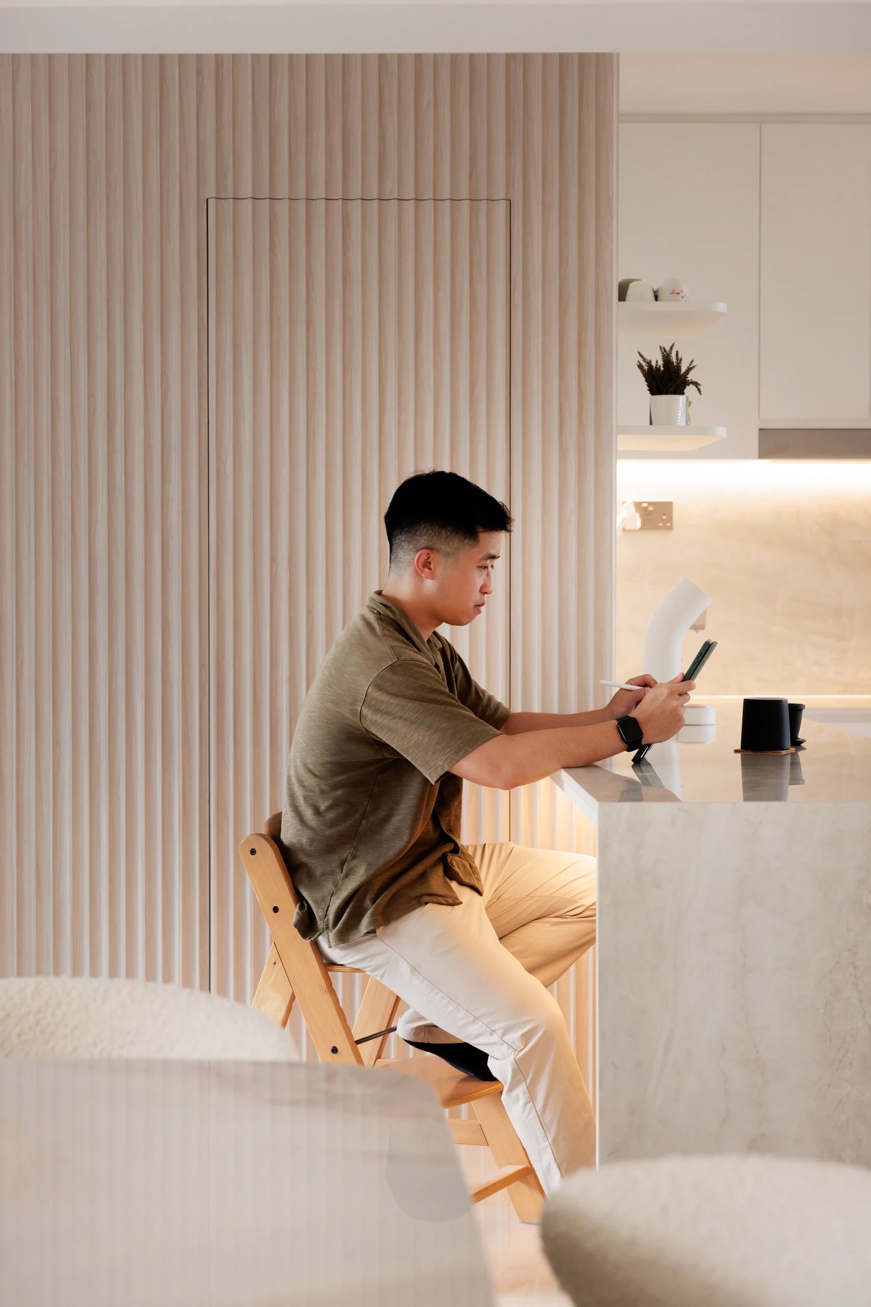 Man sitting at kitchen island with a drink and book