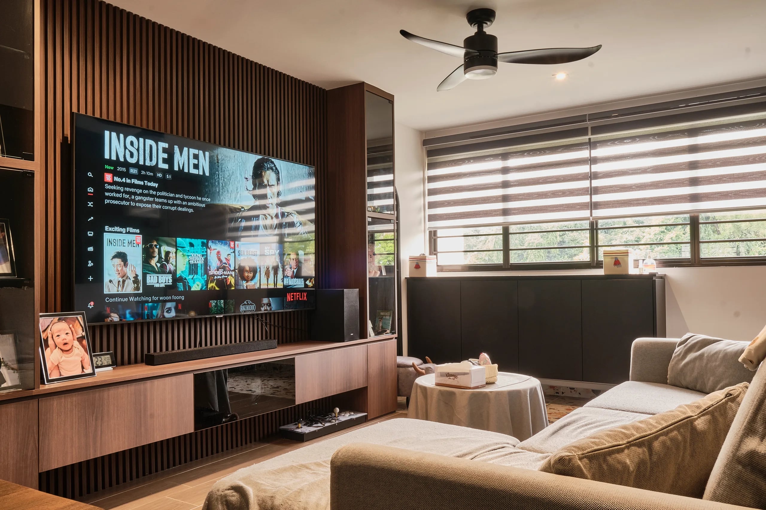 TV console feature wall in wood laminate with floating shelf, ceiling fan, blinds